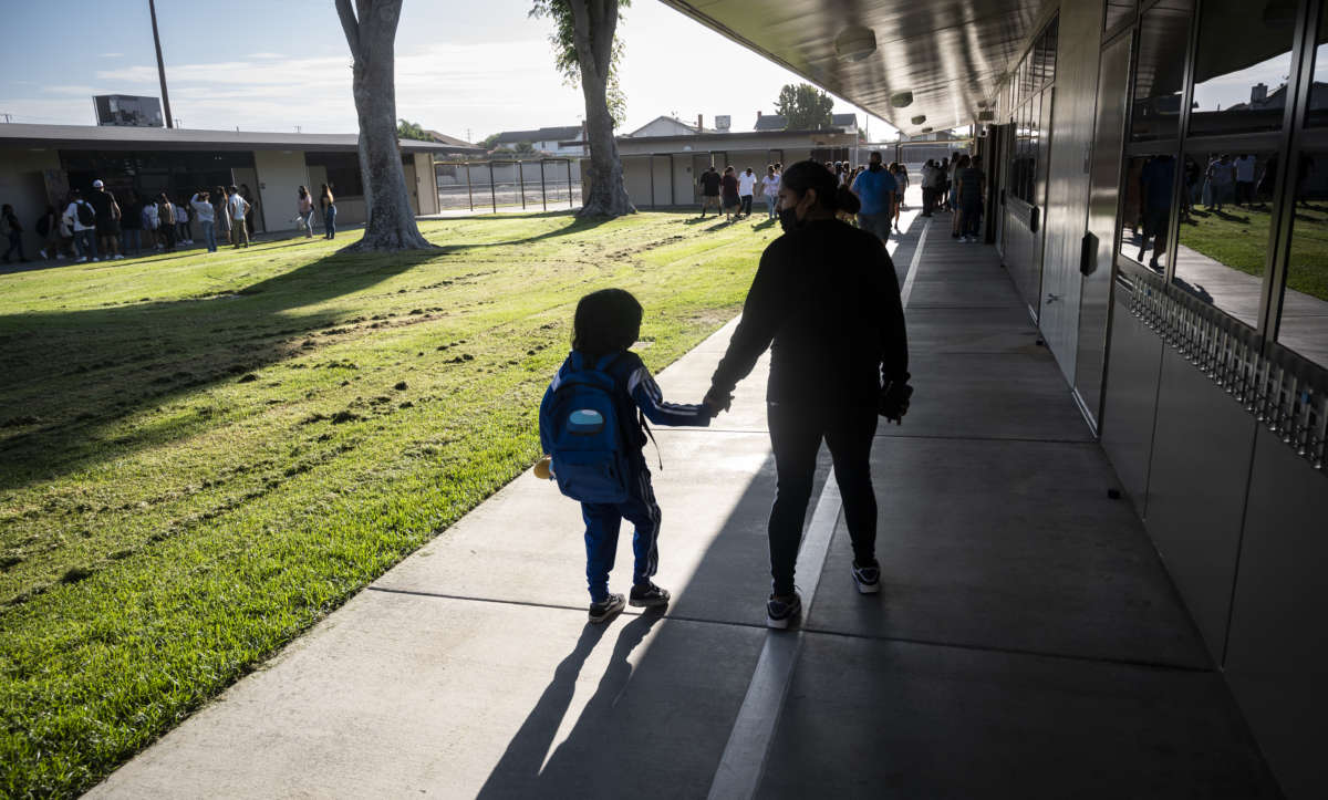 A student is walked to class to the first day of instruction at Hansen Elementary School in Anaheim, California, on August 9, 2022.