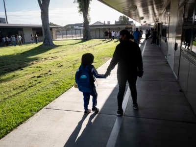 A student is walked to class to the first day of instruction at Hansen Elementary School in Anaheim, California, on August 9, 2022.