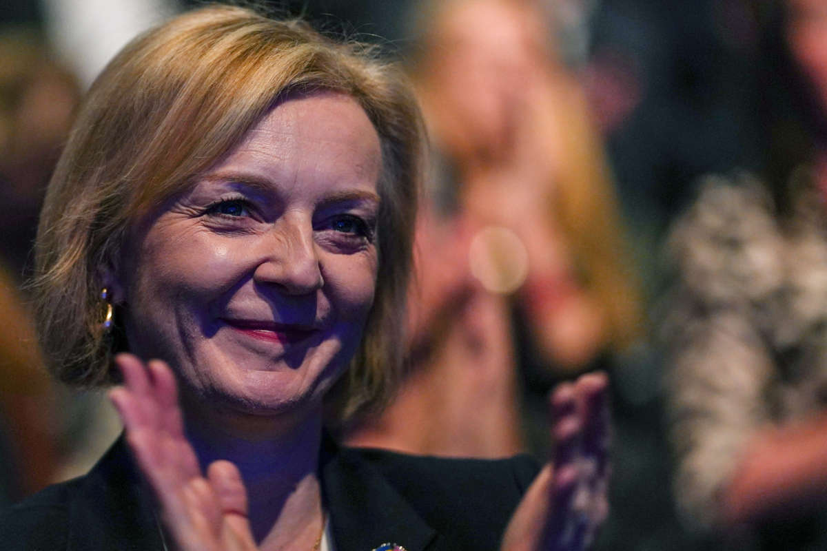 Lizz Truss claps while seated in an audience