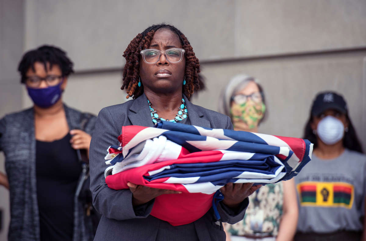 A woman holds the folded Mississippi flag