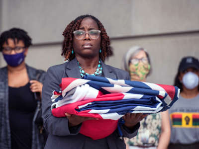 A woman holds the folded Mississippi flag