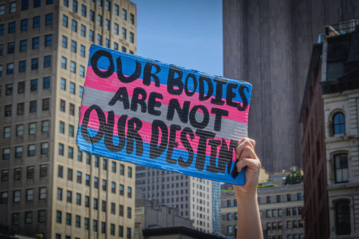 A protester holds a sign reading "OUR BODIES ARE NOT OUR DESTINIES" during a protest