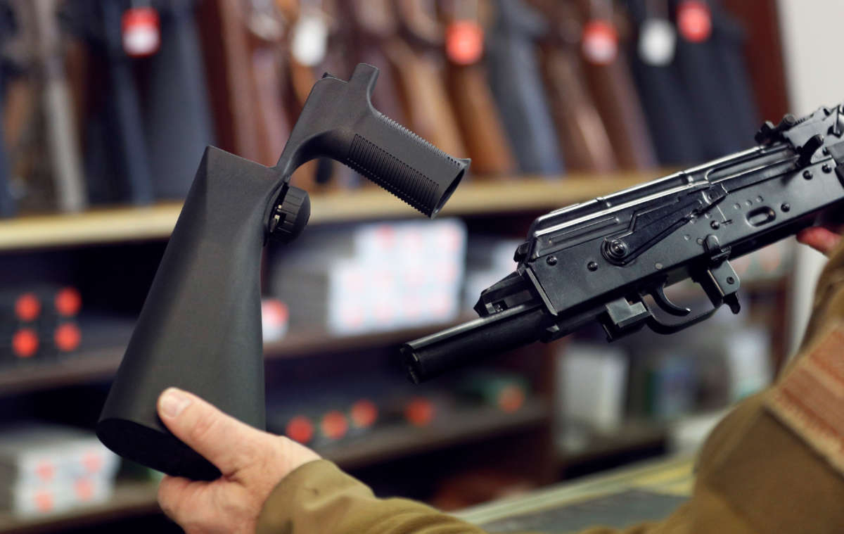 A bump stock device (left), that fits on a semi-automatic rifle to increase the firing speed, making it similar to a fully automatic rifle, is shown next to a AK-47 semi-automatic rifle (right), at a gun store