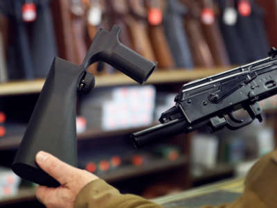 A bump stock device (left), that fits on a semi-automatic rifle to increase the firing speed, making it similar to a fully automatic rifle, is shown next to a AK-47 semi-automatic rifle (right), at a gun store