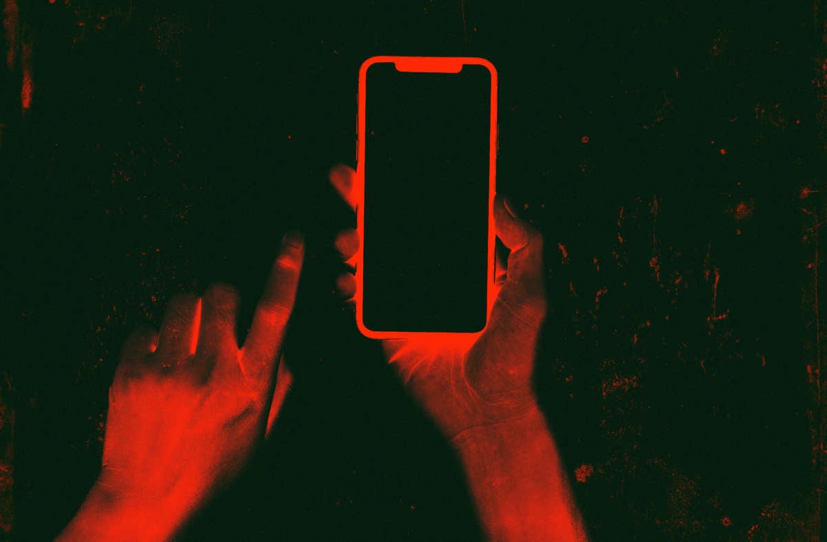 Inverted photo with red hands holding phone
