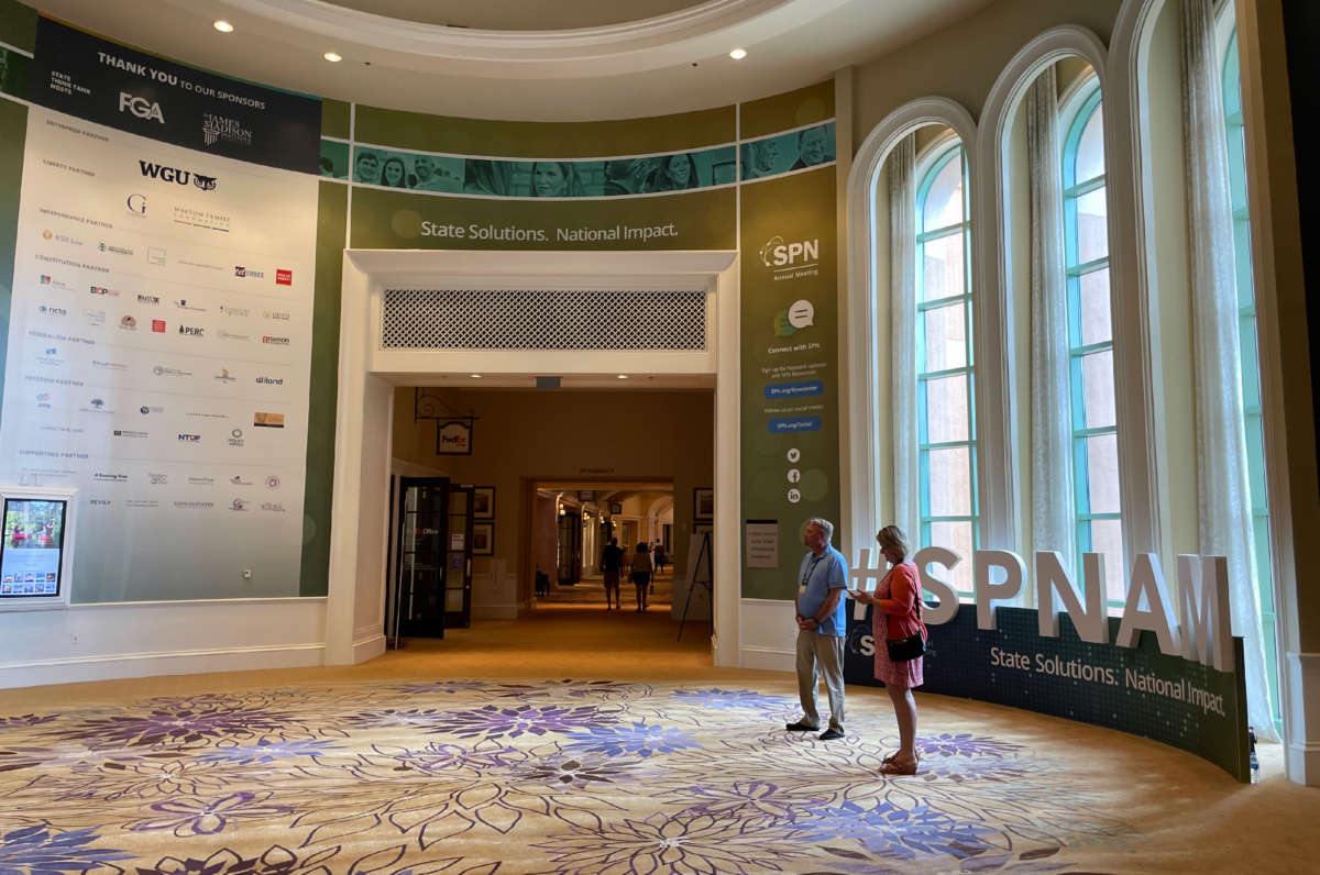 People stand by a display at the site of State Policy Network's 29th Annual Meeting on August 29, 2021.