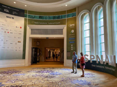 People stand by a display at the site of State Policy Network's 29th Annual Meeting on August 29, 2021.