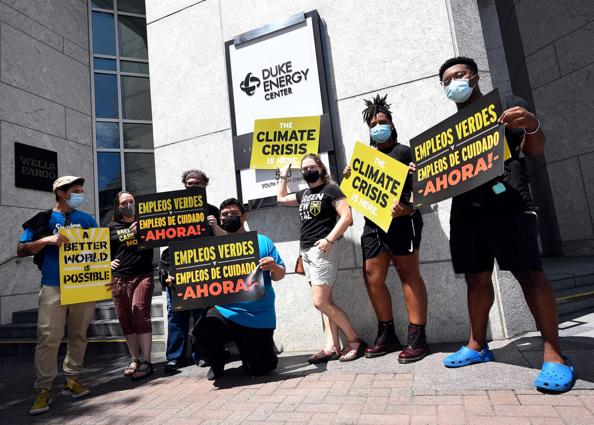 Protesters standing outside of the Duke Energy Center display signs reading "THE CLIMATE CRISIS IS HERE"