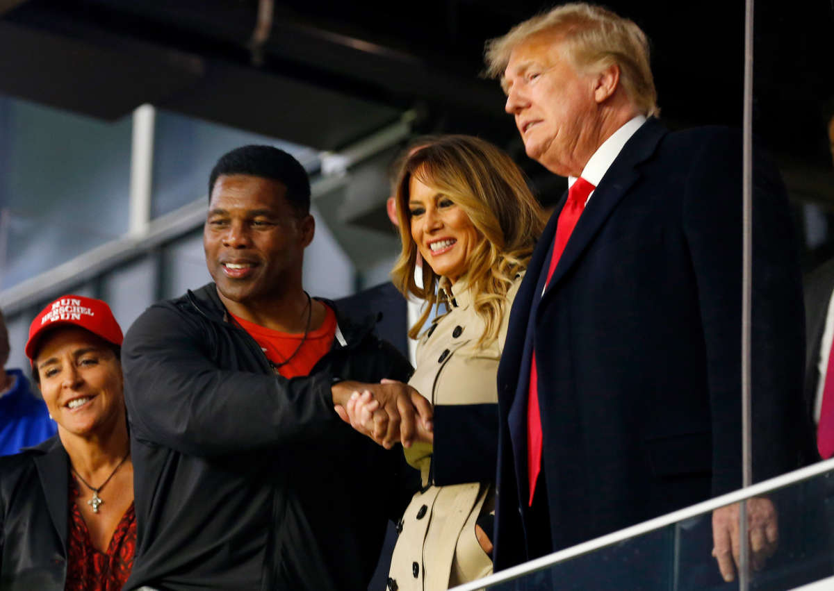 Former football player and political candidate Herschel Walker interacts with former President Donald Trump at Truist Park on October 30, 2021, in Atlanta, Georgia.