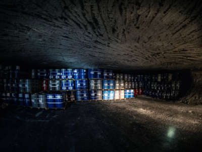 Stacked barrells of toxic waste line the claustrophobic interior of an underground storage bunker