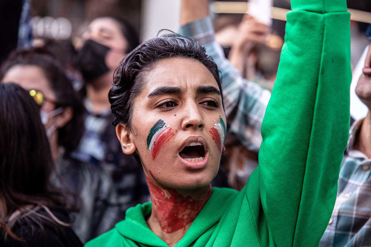 A protester with the Iranian flag painted on their face participates in an outdoor demonstration