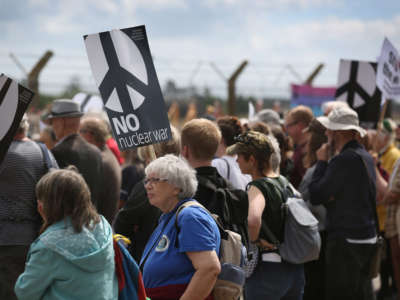 Demonstrators hold anti-nuclear war signs as they gather in the viewing area at the Royal Air Force station in Lakenheath, England, on May 21, 2022.