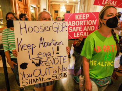 Abortion rights activists hold signs inside the Indiana State house during a special session in Indianapolis, Indiana, on August 5, 2022.