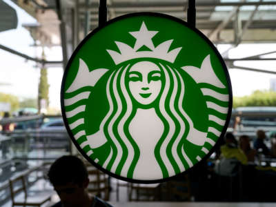 Travelers are silhouetted while sitting under Starbucks Coffee logo in the arrivals hall at Terminal 1 in Humberto Delgado International Airport Humberto Delgado International Airport on October 7, 2022, in Lisbon, Portugal.