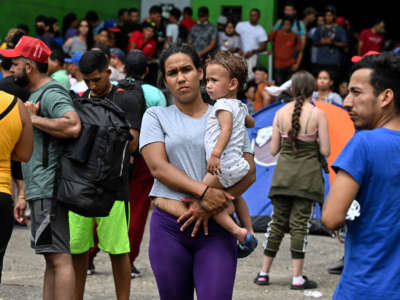 A Venezuelan migrant holds a child in her arms upon arriving at an improvised shelter in Panama City, on October 23, 2022.