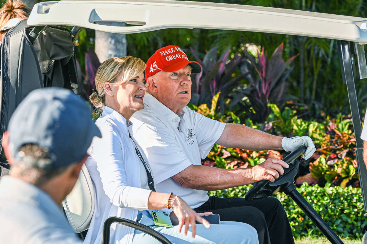 Trump looks surprised by something as he drives a golf cart