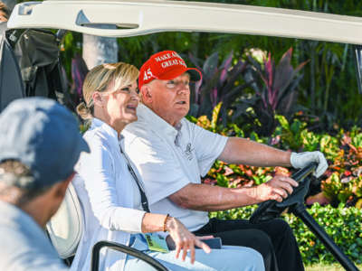 Trump looks surprised by something as he drives a golf cart