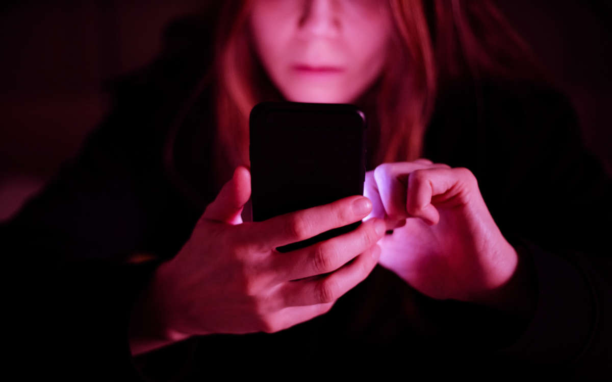 Woman looks at cell phone with reddish-pink glow