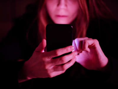 Woman looks at cell phone with reddish-pink glow