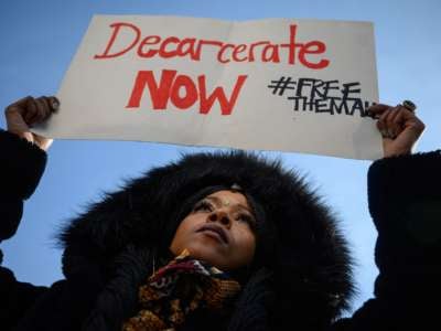 Protestor holds "Decarcerate Now" sign