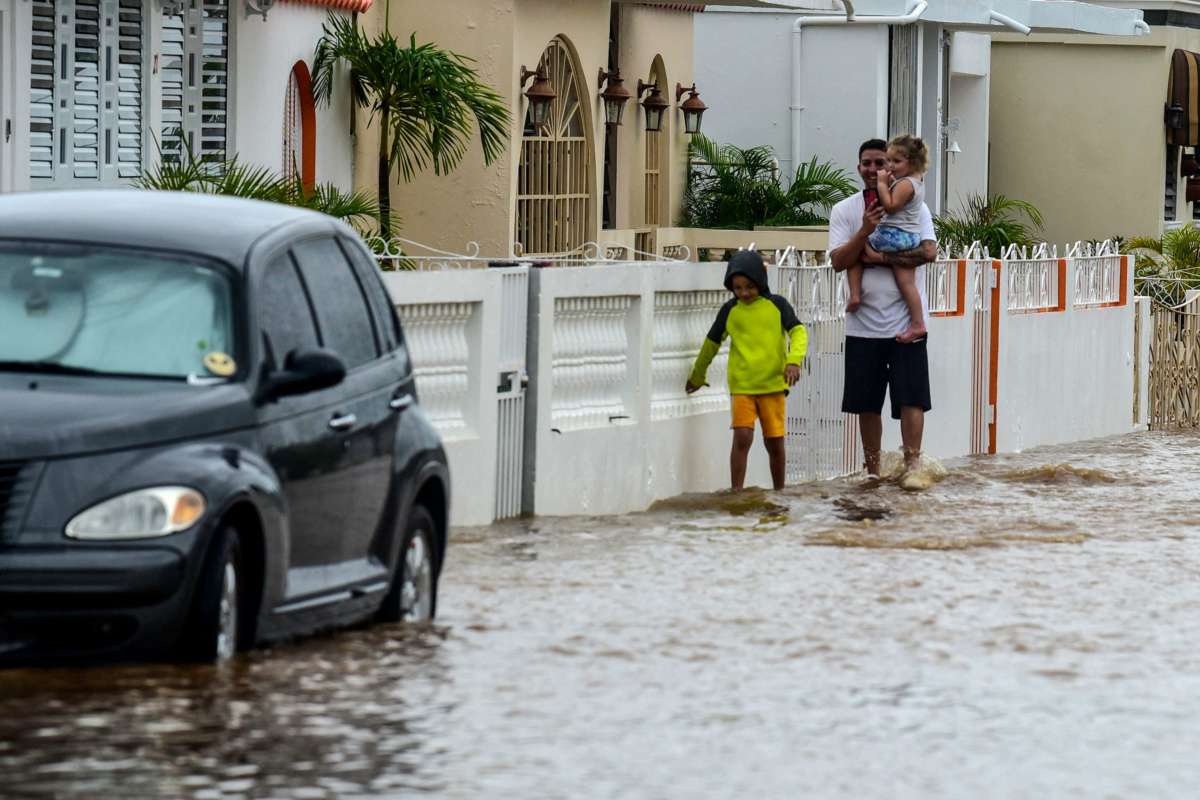 A man and two children walk in a flooded street after the passage of Hurricane Fiona in Salinas, Puerto Rico, on September 19, 2022.