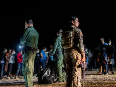 A National Guard officer looks around at migrant families after they crossed the Rio Grande into the U.S. on May 5, 2022, in Roma, Texas.