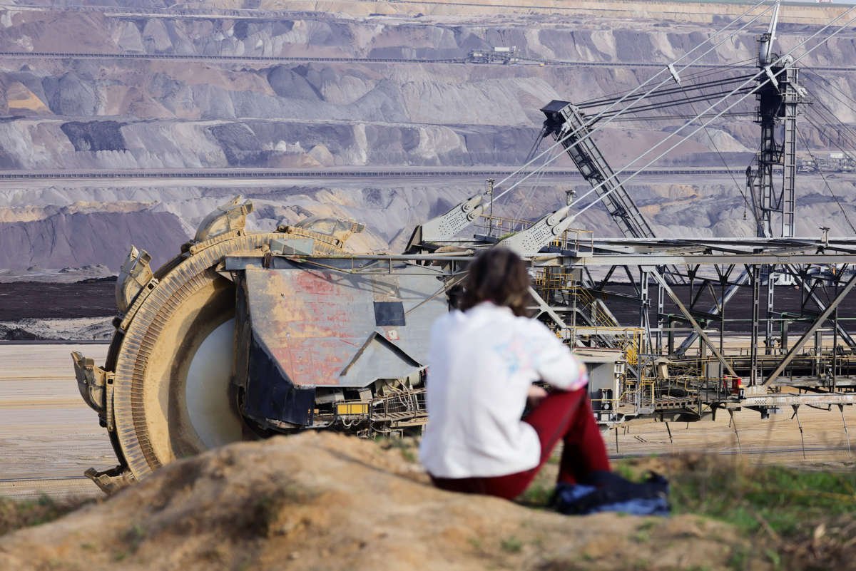 A person looks at excavation equipment from the top of a nearby hill