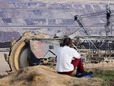 A person looks at excavation equipment from the top of a nearby hill