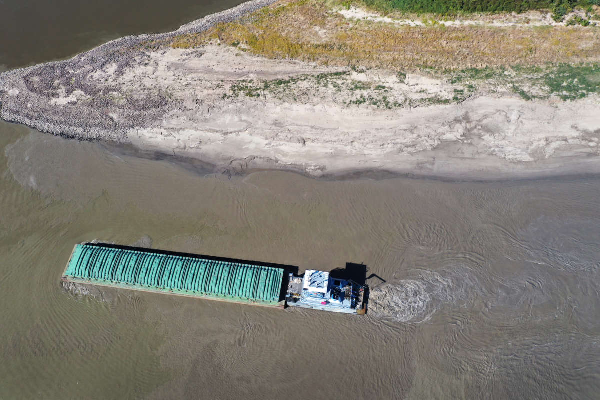 a tugboat pushes a barge through a severely lowered Mississippi river