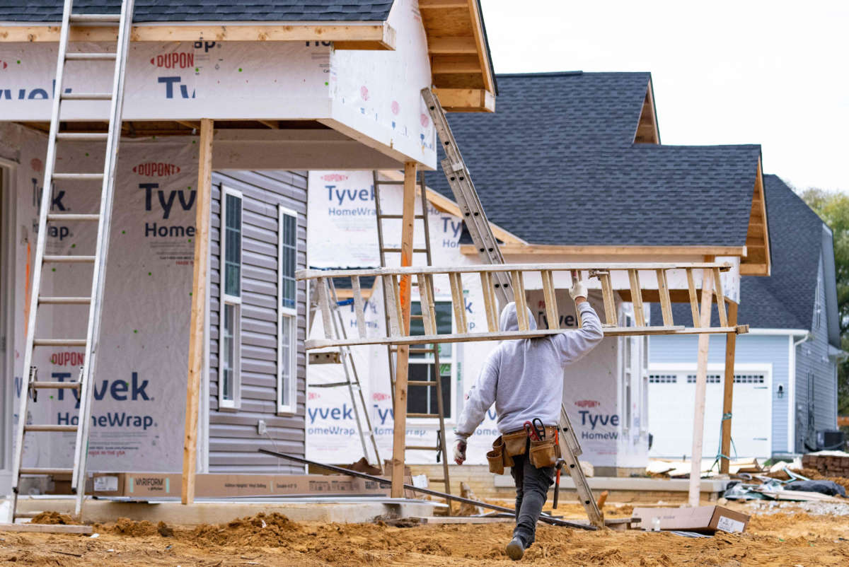 A man carries a ladder through new home construction in Trappe, Maryland, on October 28, 2022.