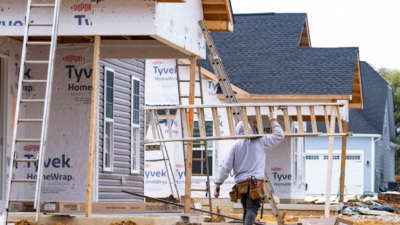 A man carries a ladder through new home construction in Trappe, Maryland, on October 28, 2022.