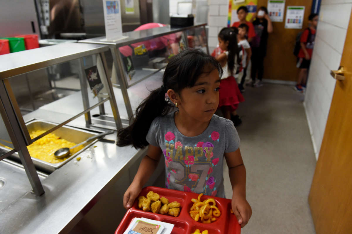 A child takes her tray back to her seat during lunch at North Star Elementary School on June 5, 2017, in Thornton, Colorado.