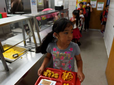 A child takes her tray back to her seat during lunch at North Star Elementary School on June 5, 2017, in Thornton, Colorado.