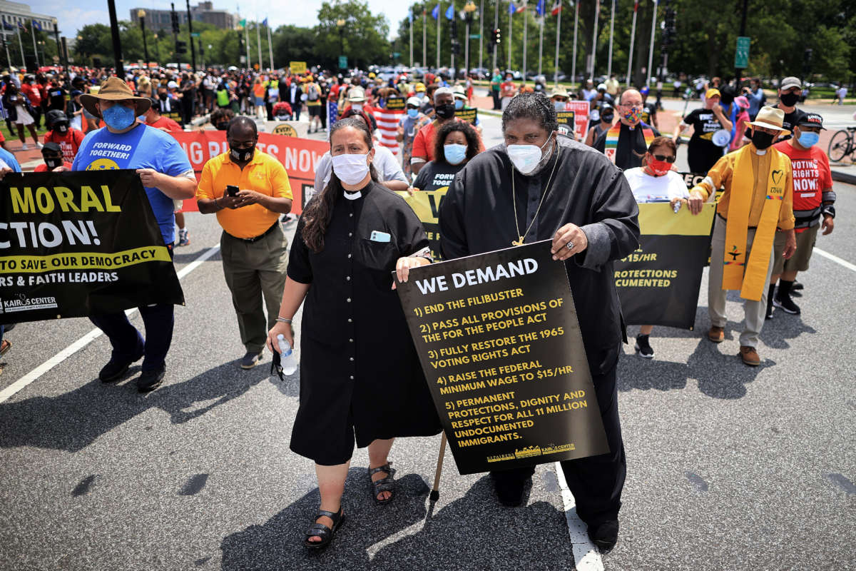Rev. Dr. William Barber II, center, and Rev. Dr. Liz Theoharis, left, march with hundreds of protesters on Capitol Hill to demand an end to the filibuster, stronger voting rights, immigration reform, a $15 minimum wage and other progressive policies on August 2, 2021, in Washington, D.C.