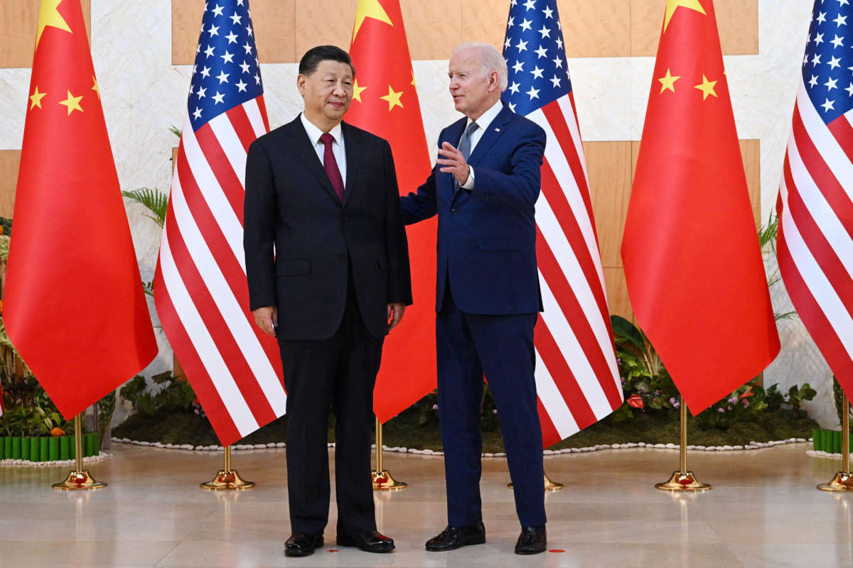 Joe Biden speaks with Chinese President Xi Jinping in front of US and Chinese flags