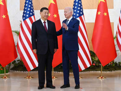 Joe Biden speaks with Chinese President Xi Jinping in front of US and Chinese flags