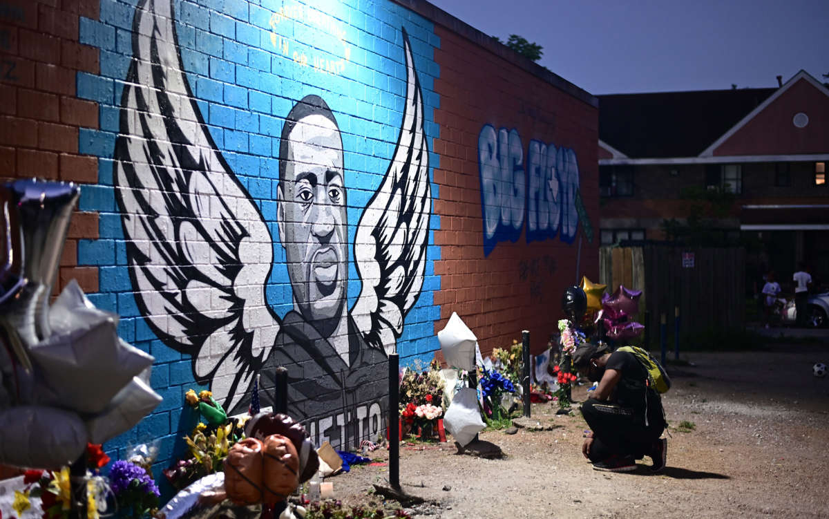 A man pays his respects and kneels in front of a mural of George Floyd in Houston, Texas, on June 8, 2020.