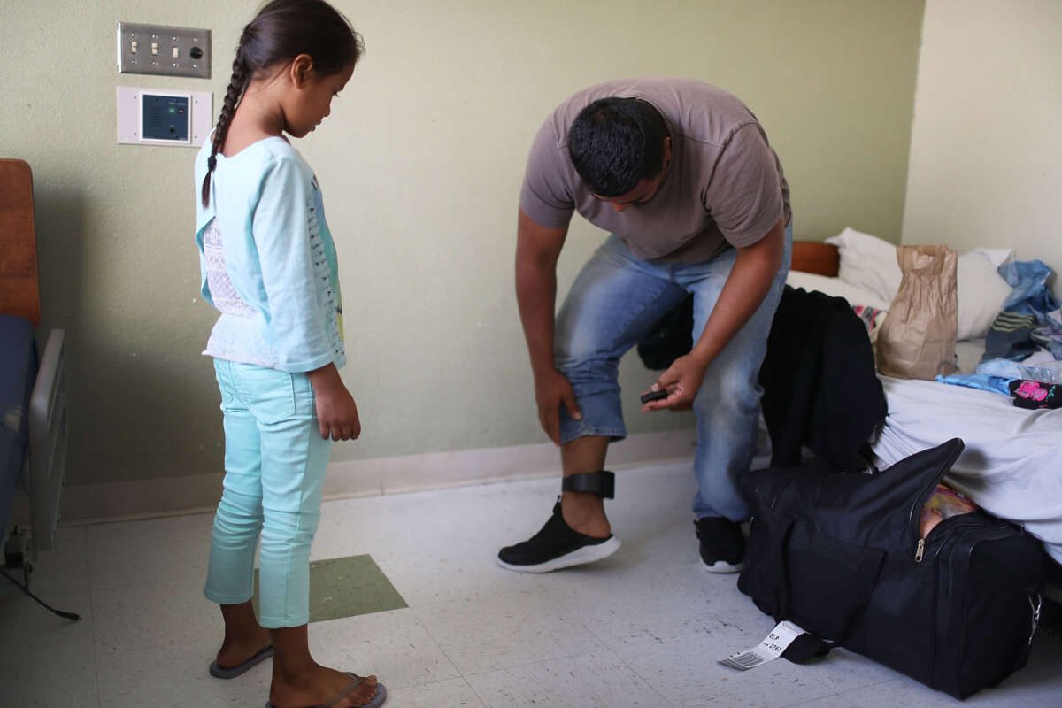 Selena watches as her father Luis (only first name was provided) works on changing the battery in his ankle monitor as they are cared for in an Annunciation House facility after they were reunited on July 26, 2018, in El Paso, Texas.