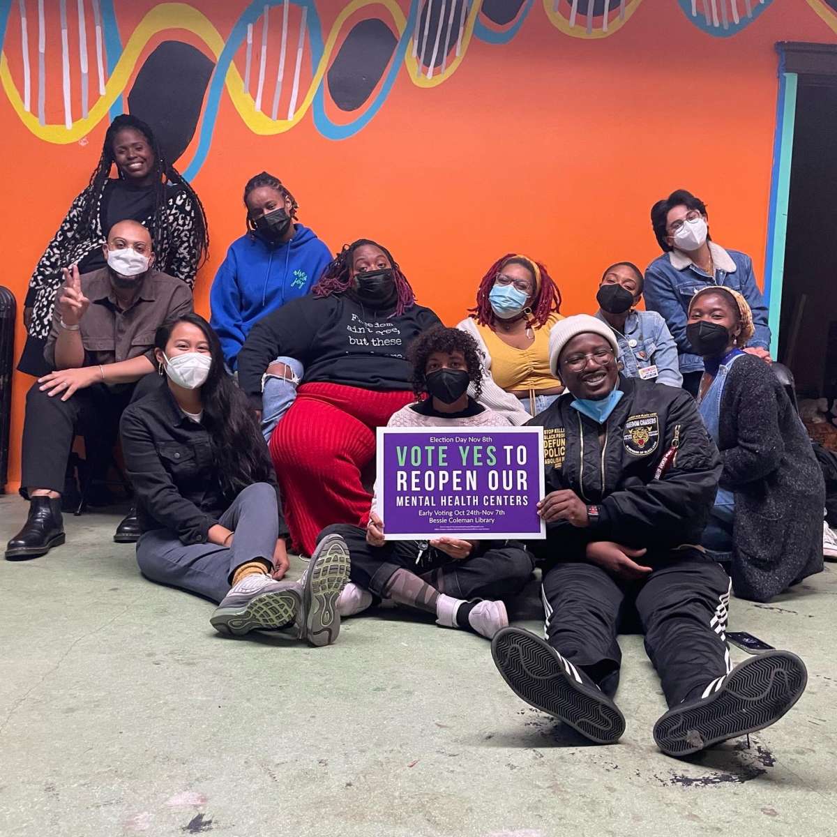 Election Day canvassers pose for a picture holding a sign saying, Vote YES to reopen our mental health centers at The Breathing Room and Garden in the 20th ward neighborhood of Garfield Park. 