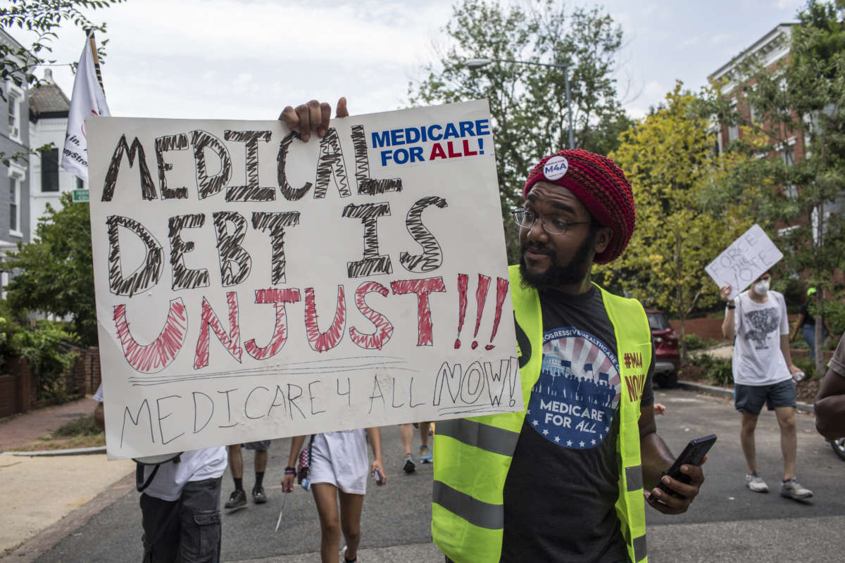 A man holding a sign with "medical debt is unjust" written on it as he takes part in the March for Medicare for All near the Capitol in Washington, D.C.