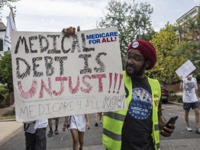 A man holding a sign with "medical debt is unjust" written on it as he takes part in the March for Medicare for All near the Capitol in Washington, D.C.