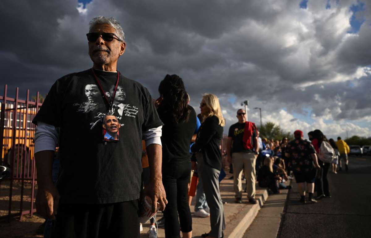 A person waits in line to enter a "Get Out the Vote" rally at Cesar Chavez High School as storm clouds gather overhead in Phoenix, Arizona on November 2, 2022.