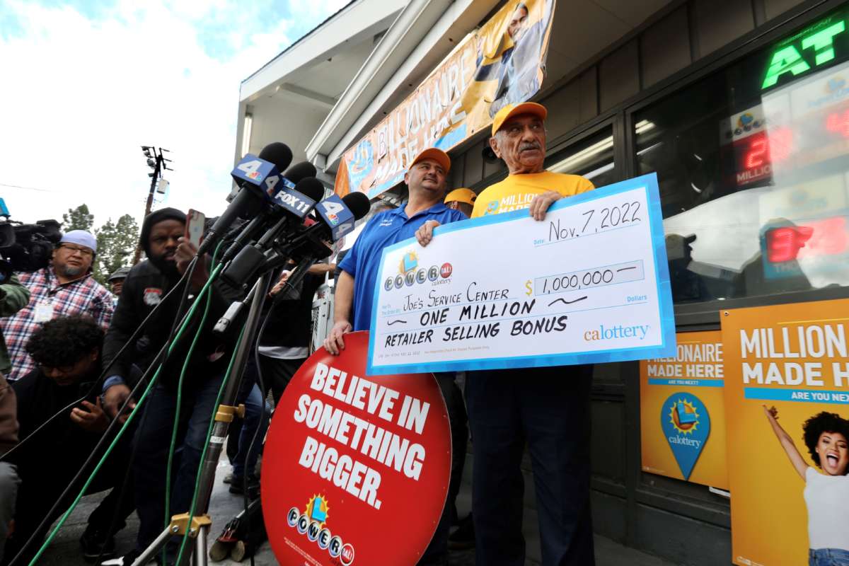Business owner Joe Chahayed (right) holds a Powerball bonus check outside Joe's Service Center, which sold the winning Powerball ticket of $2.04 billion in Altadena, California on November 8, 2022.