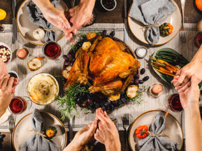 Family holding hands and pray during Thanksgiving dinner