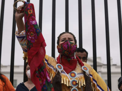 A demonstrator holds up her fist in front of the White House during a climate march in honor of Indigenous Peoples’ Day on October 11, 2021, in Washington, D.C.