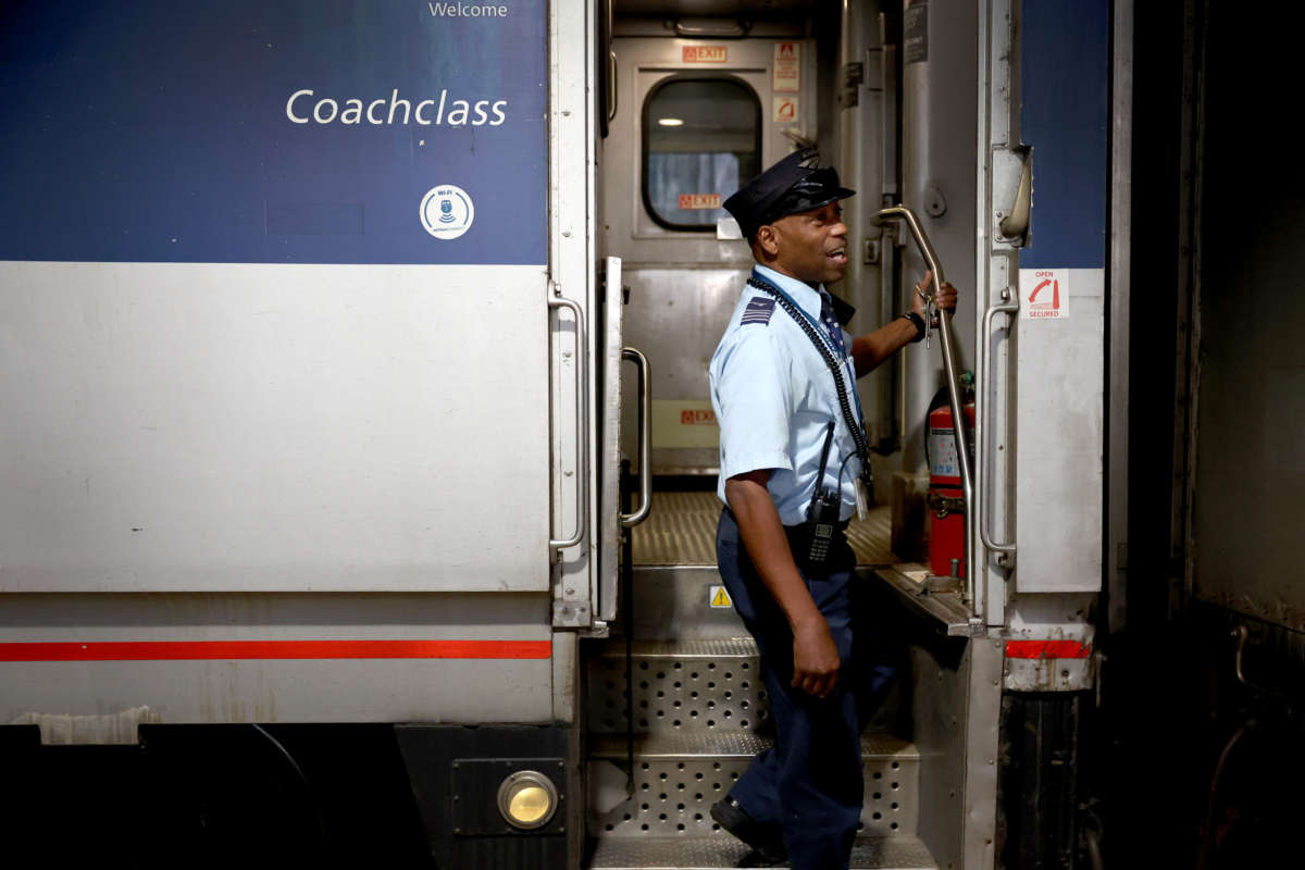 Amtrak conductor helps board passengers on a train to Milwaukee at Union Station