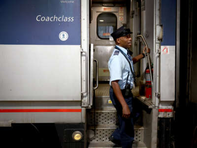 Amtrak conductor helps board passengers on a train to Milwaukee at Union Station