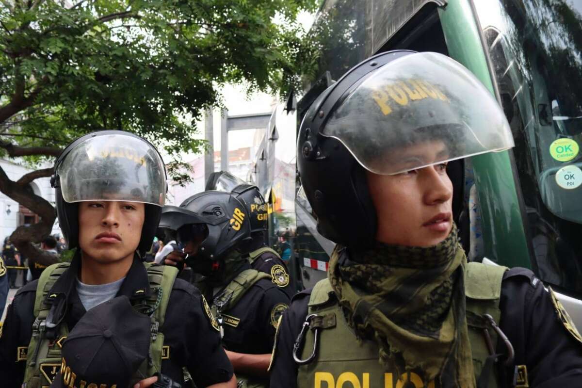 Heavily armed members of the Peruvian National Police stand outside the Peasant Confederation of Peru in Lima on December 17, 2022, as a 12-hour raid is conducted. Around 60 protesters from outside Lima had been staying at the Confederation's office during the days of protest.