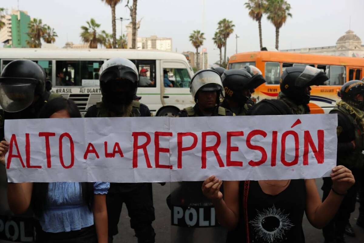 Protesters hold a sign saying “alto a la represión” (stop the repression) in front of a line of riot police during the 12-hour raid on the Peasant Confederation of Peru in Lima on December 17, 2022.