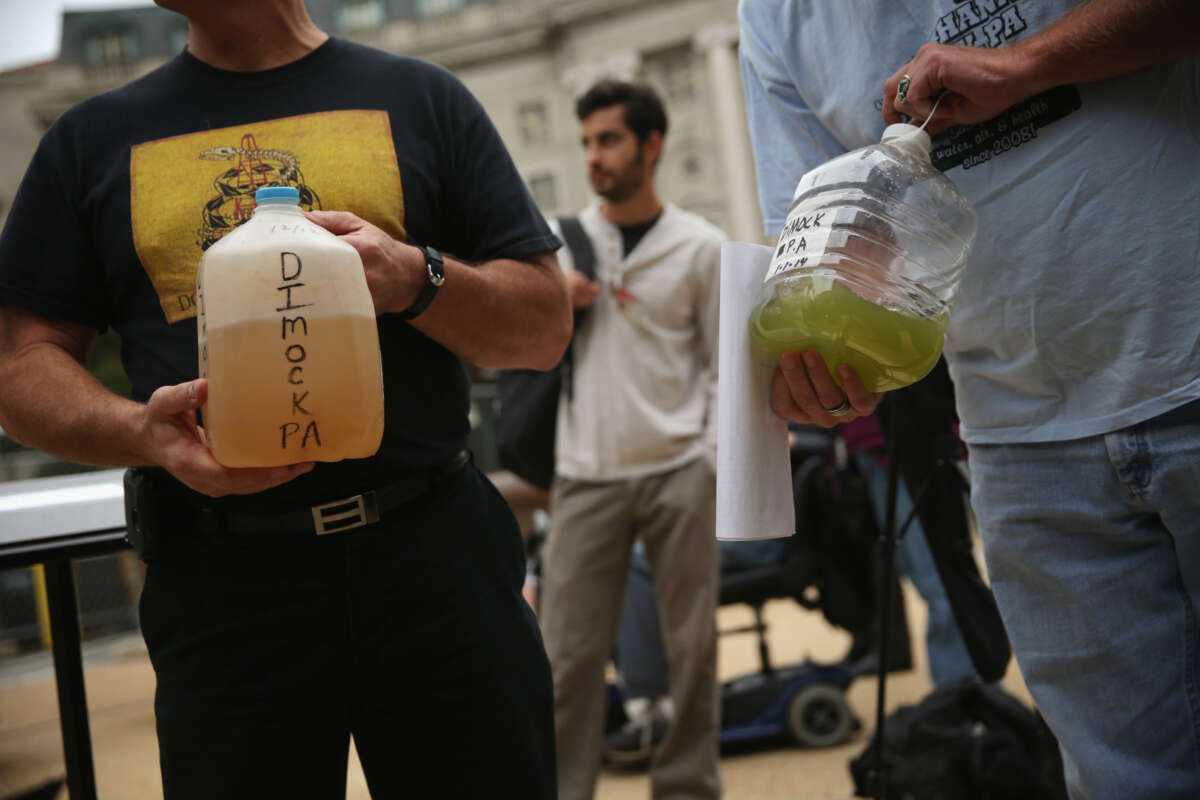 Craig Stevens, left, of Silver Lake Township, Pennsylvania, and Ray Kemble, right, of Dimock, Pennsylvania, show water samples collected from Dimock, Pennsylvania, during a rally on fracking-related water investigations, on October 10, 2014, outside the EPA's Headquarters in Washington, D.C.